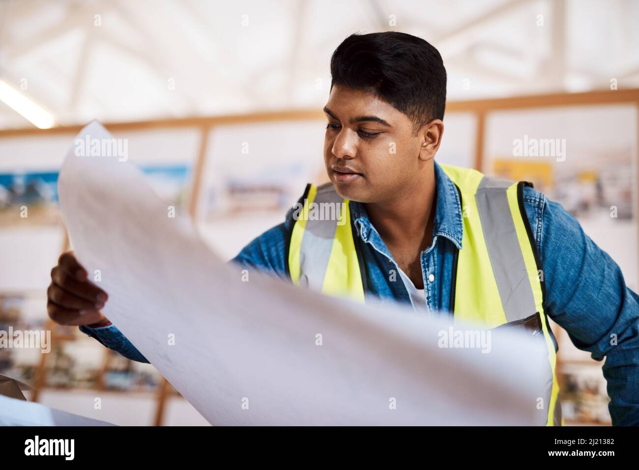 Ich kann es kaum erwarten zu sehen, wie sich das herausstellt. Aufnahme eines jungen Architekten, der in seinem Büro eine Blaupause ansieht. Stockfoto
