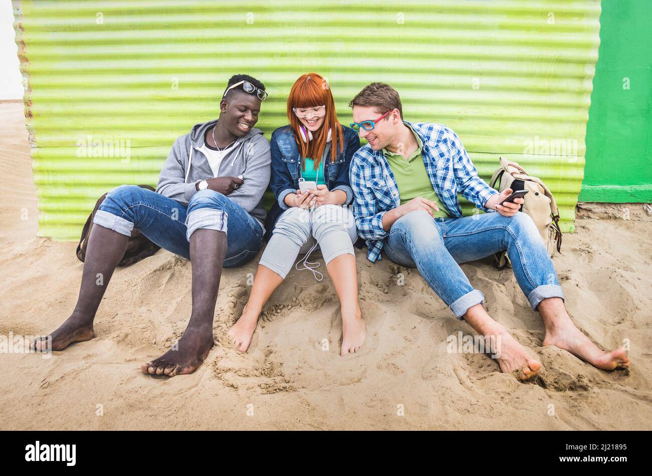Gruppe glücklicher multirassischer Freunde, die gemeinsam mit dem Handy Spaß haben - Junge Hipster-Menschen, die auf dem sozialen Netzwerk commun mit dem Smartphone süchtig sind Stockfoto