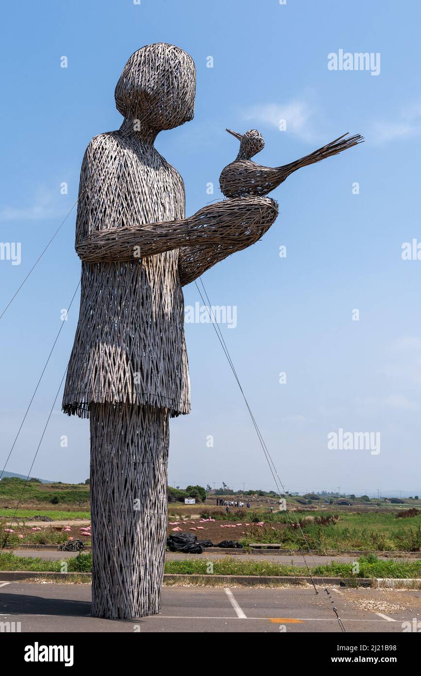 Eine hohe Korbskulptur einer Frau, die einen Vogel am Ort des Seodal-Massakers von 1950 in der Nähe des Flugfeldes Altteureu auf der Insel Jeju in Südkorea hält. Stockfoto