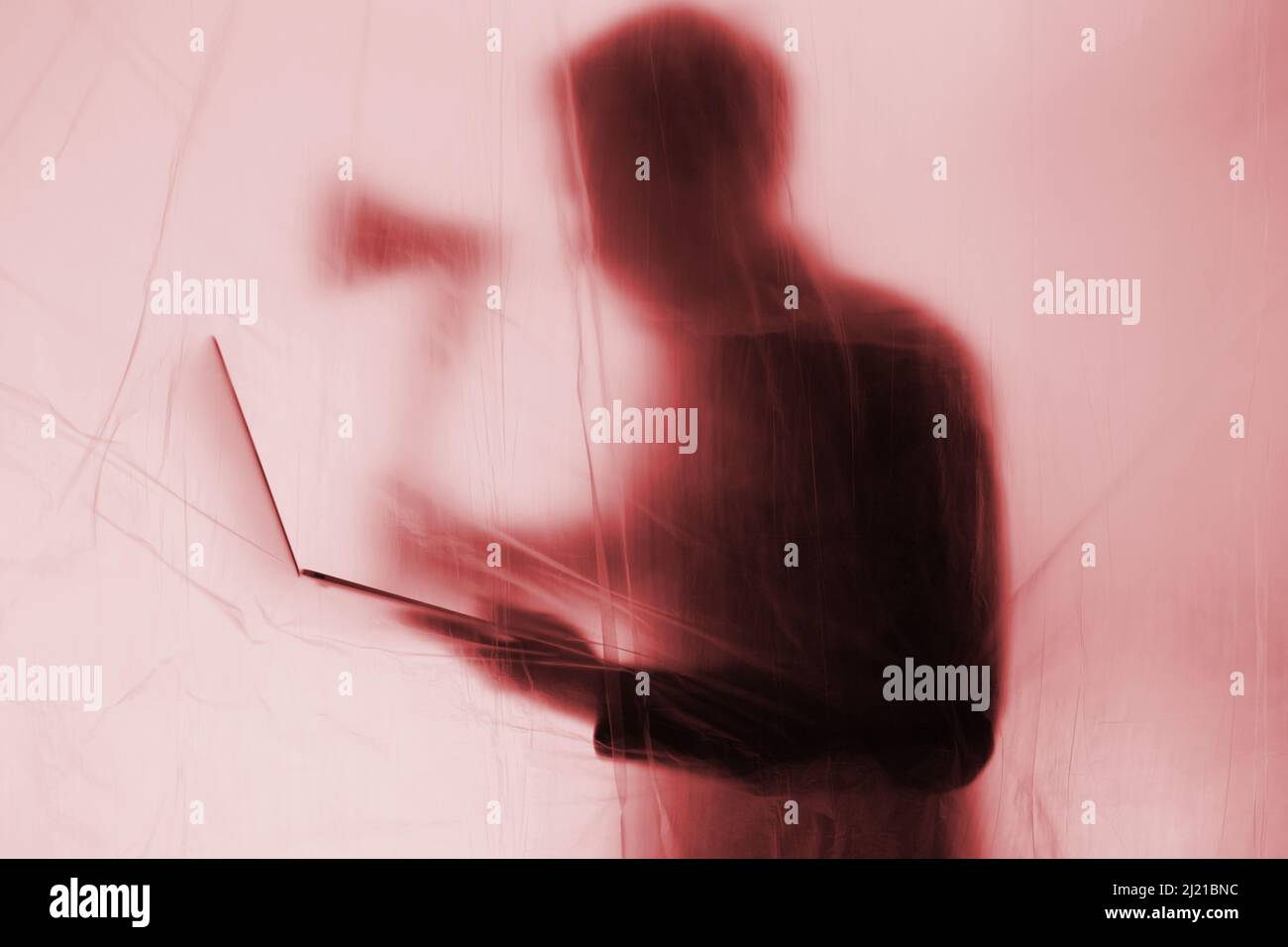 Anonymous Hacker begeht Cyberkriminalität mit Notebook in der Hand. Eine Axt wird gehalten, um das gewaltsam Eindringen von IT-Systemen zur Ausnutzung zu symbolisieren. Stockfoto