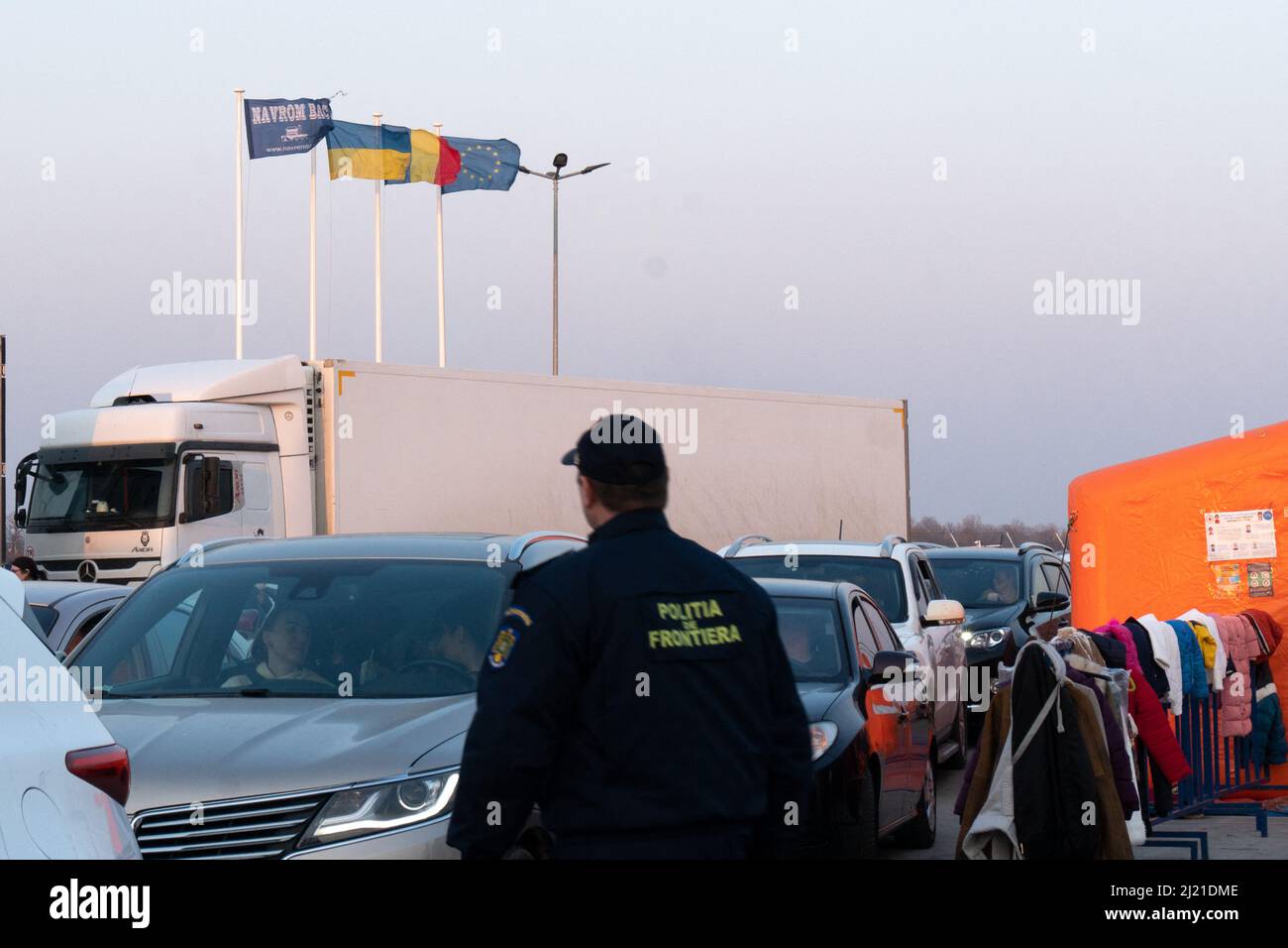 Grenzpolizisten ergreift am Donnerstag, den 24. März, die Auto- und Lkw-Warteschlange am Grenzübergang in Isaccea, Rumänien, 2022. Neben ihnen werden gespendete Kleider auf einem Zaun, direkt neben dem Zeltausgang der Triage, organisiert. Foto von Anca Gheonea/ABACAPRESS.COM Stockfoto