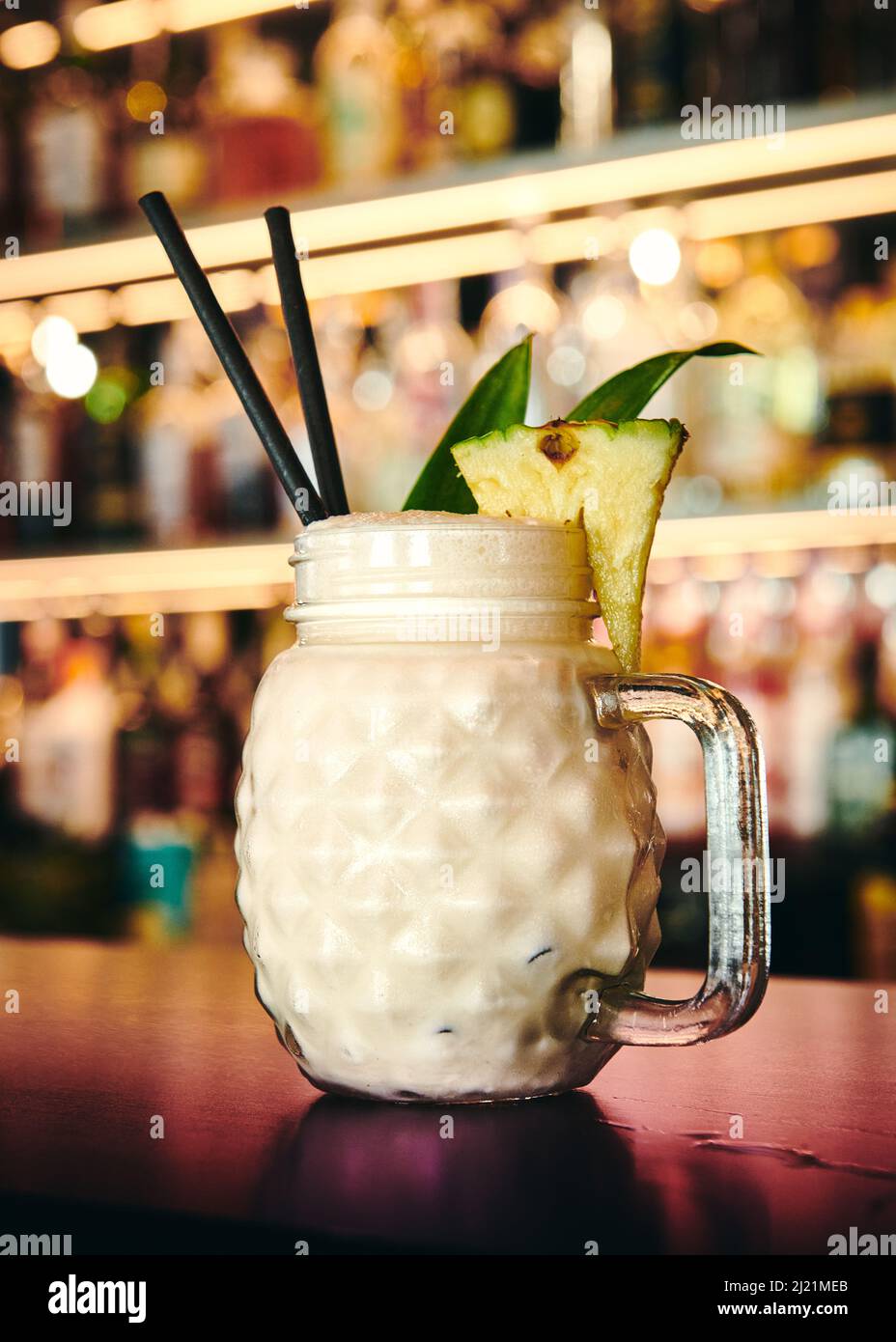 Ein Pina Colada Cocktail vor einer attraktiven Bar Stockfoto