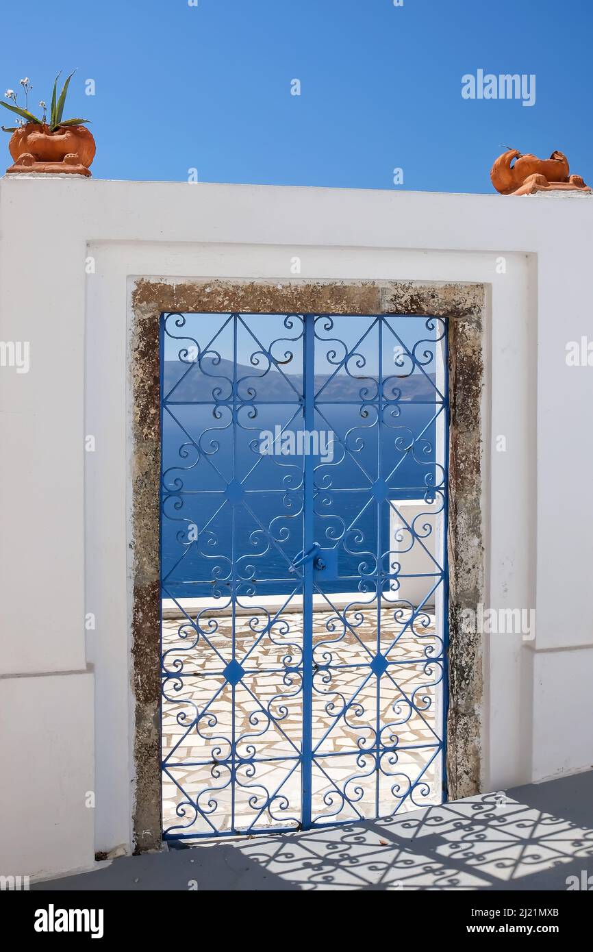 Eine außen dekorierte Tür mit Blumenpflanzen auf dem Dach einer Villa und Blick auf die ägäis in Fira Santorini Stockfoto