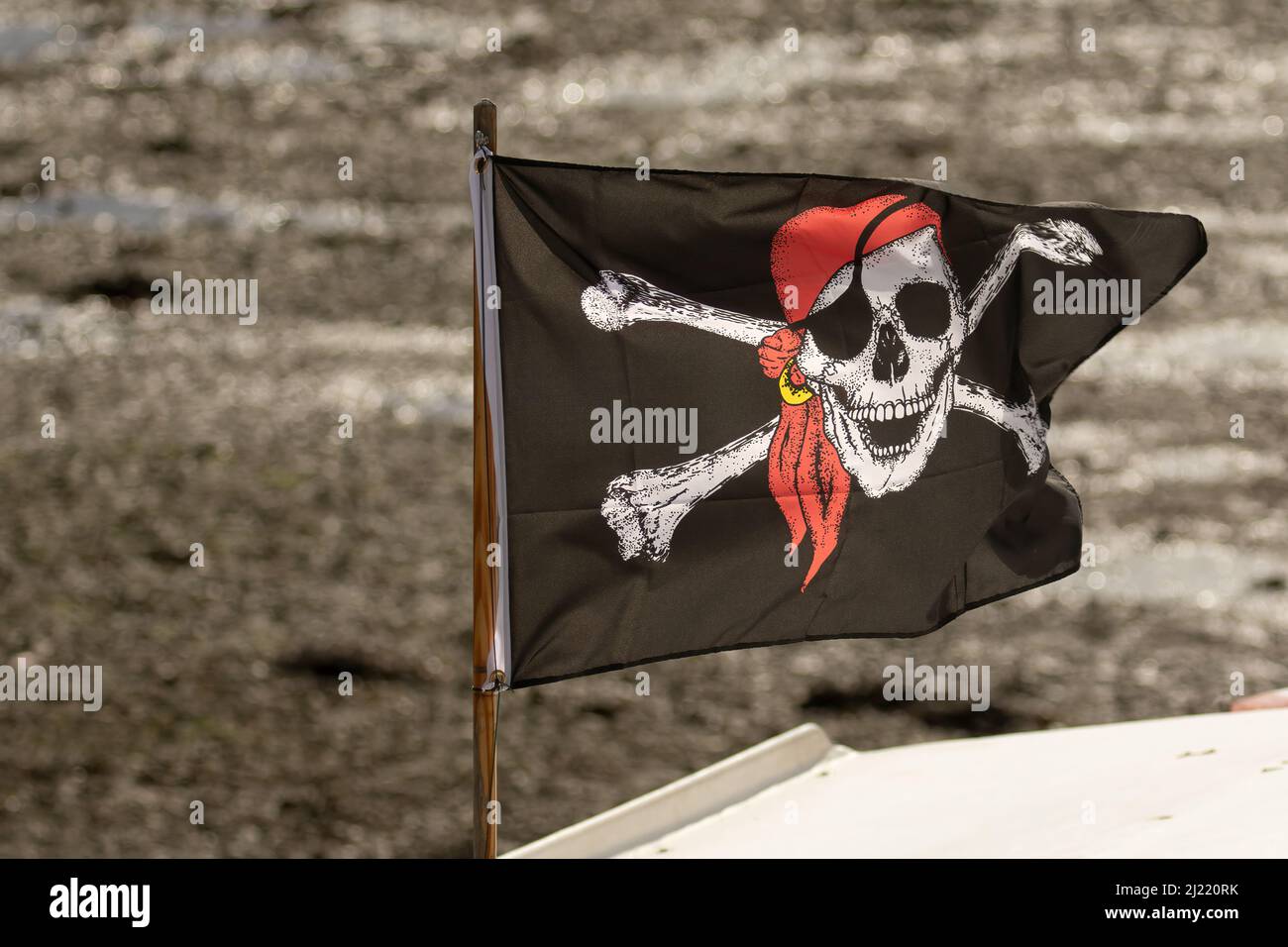 Pirate Skull und Kreuzknochen-Flagge auf einem kleinen Boot im Hafen, Großbritannien Stockfoto