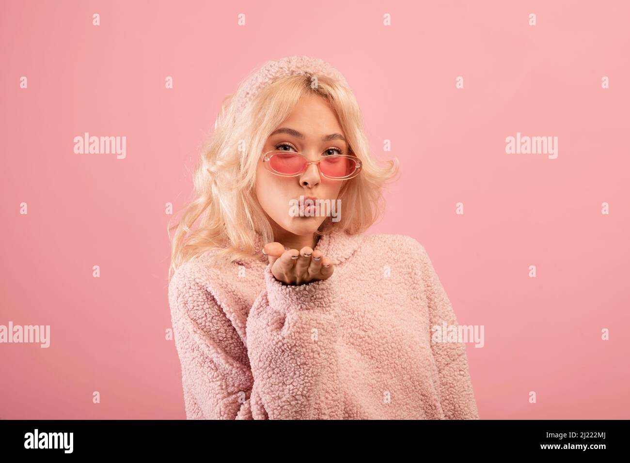 Ziemlich stilvolle Dame weht Luftkuss auf die Kamera, verspielte Frau flirty, Senden ihrer Liebe, rosa Studio-Hintergrund Stockfoto