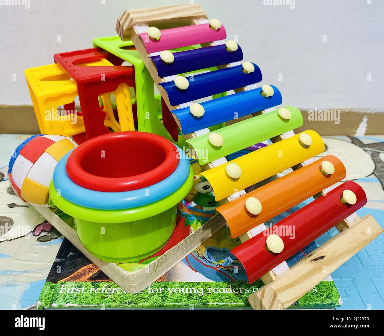 Eine Nahaufnahme der bunten Spielzeuge mit Blöcken, Xylophon, einem Ball, einem Buch und Tassen Stockfoto