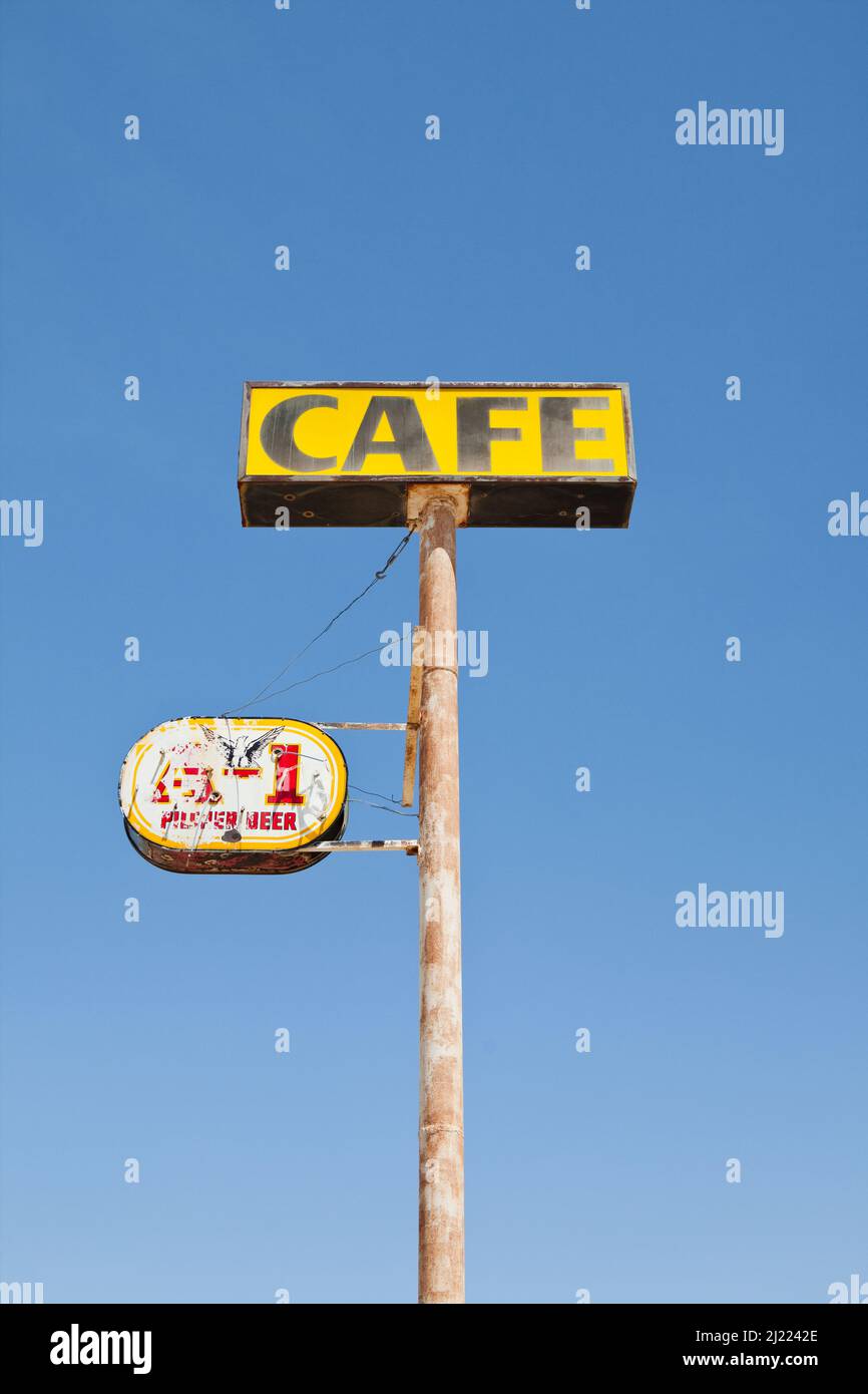 Cafe-Schild, verrostet und verblasst, auf einem Pfahl, blauer Himmel im Hintergrund. Stockfoto