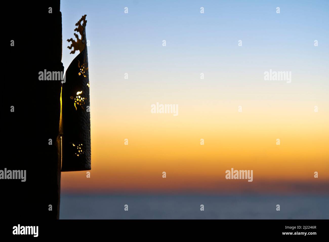 Eine Laterne grills an einer Wand, Silhouette gegen den Sonnenuntergang Himmel. Stockfoto