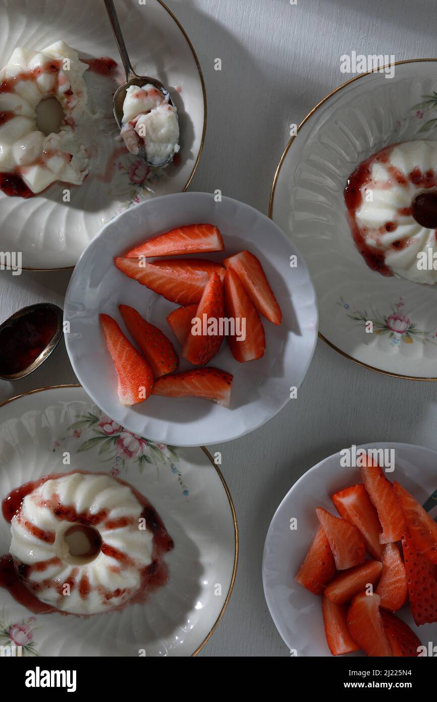 Italienische Dessert-Panna Cotta mit Obstmarmelade und frischen Erdbeerstücken auf Tellern. Draufsicht Stockfoto