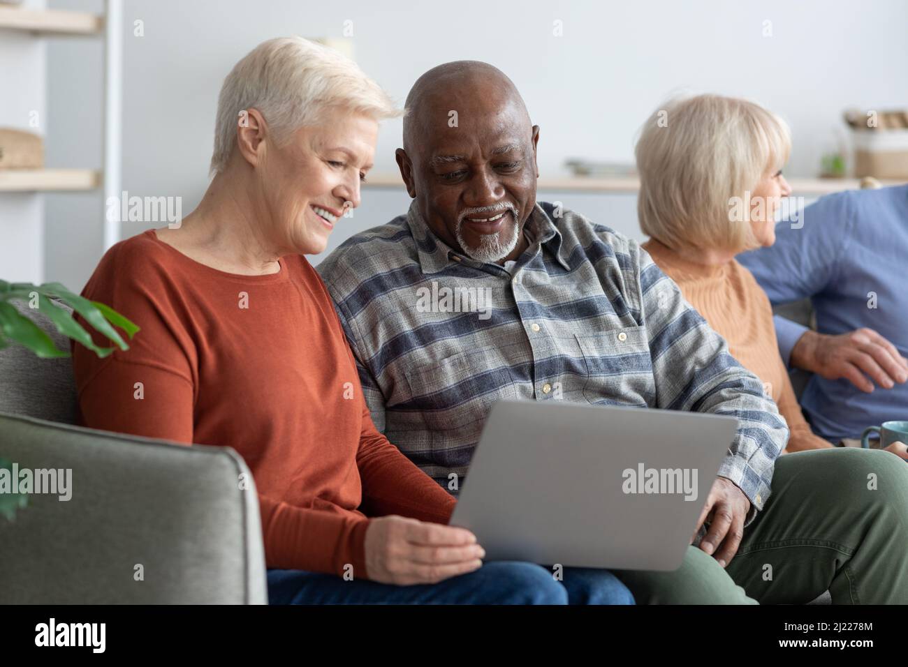 Lächelnder älterer schwarzer Mann und kaukasische Frau mit Laptop Stockfoto