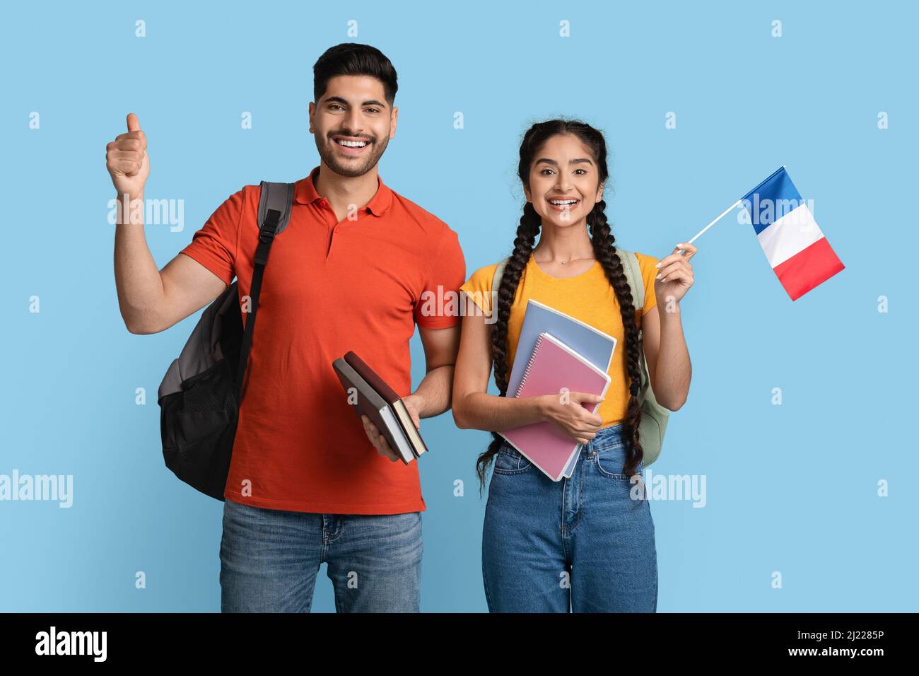 Studieren In Frankreich. Arabischer Mann Und Frau Mit Arbeitsbüchern Und Französischer Flagge Stockfoto