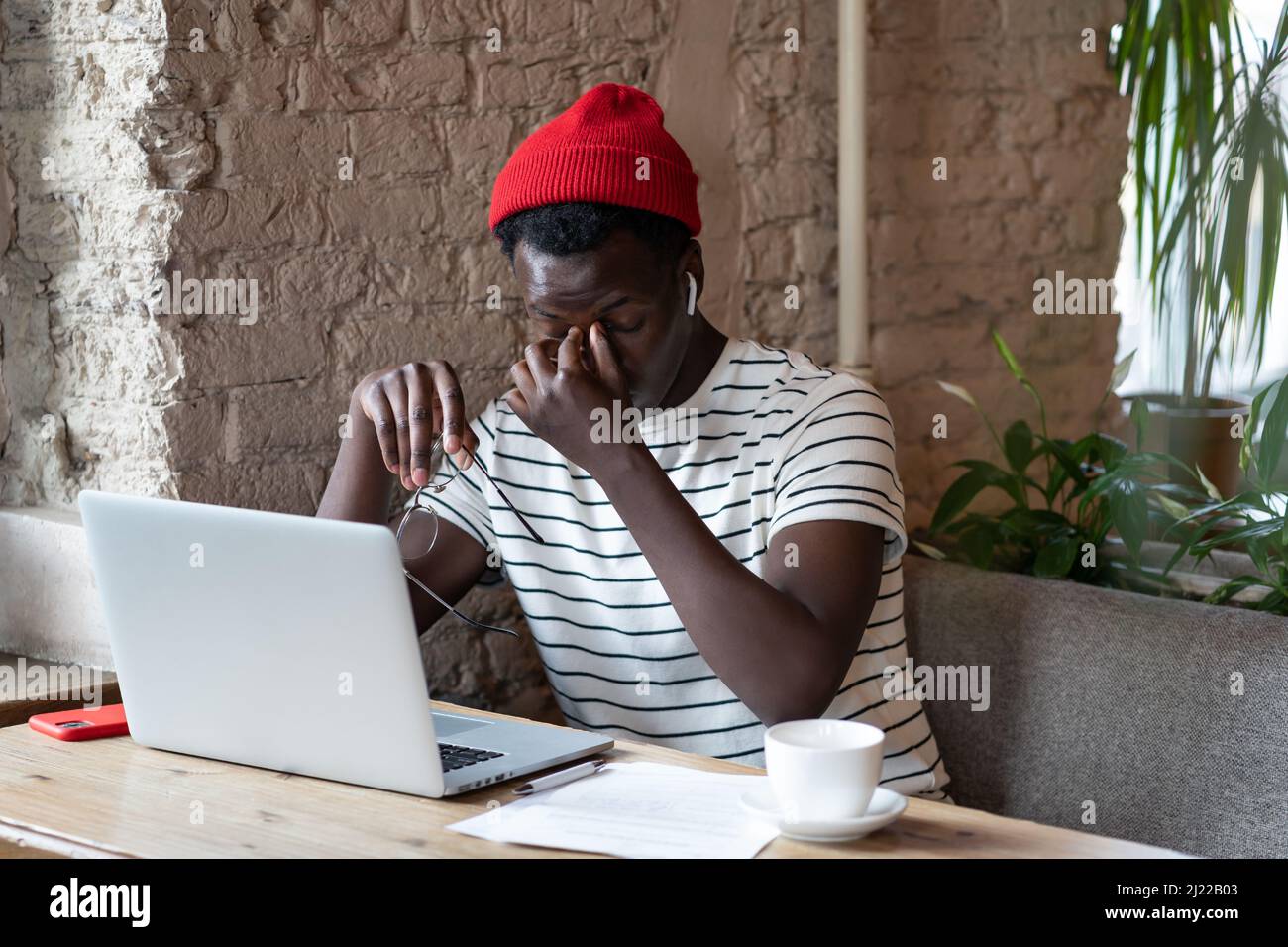 Müde gestresst schwarzen Kerl nehmen Brille fühlen Augenbelastung nach Überstunden Computer Arbeit im Café Stockfoto