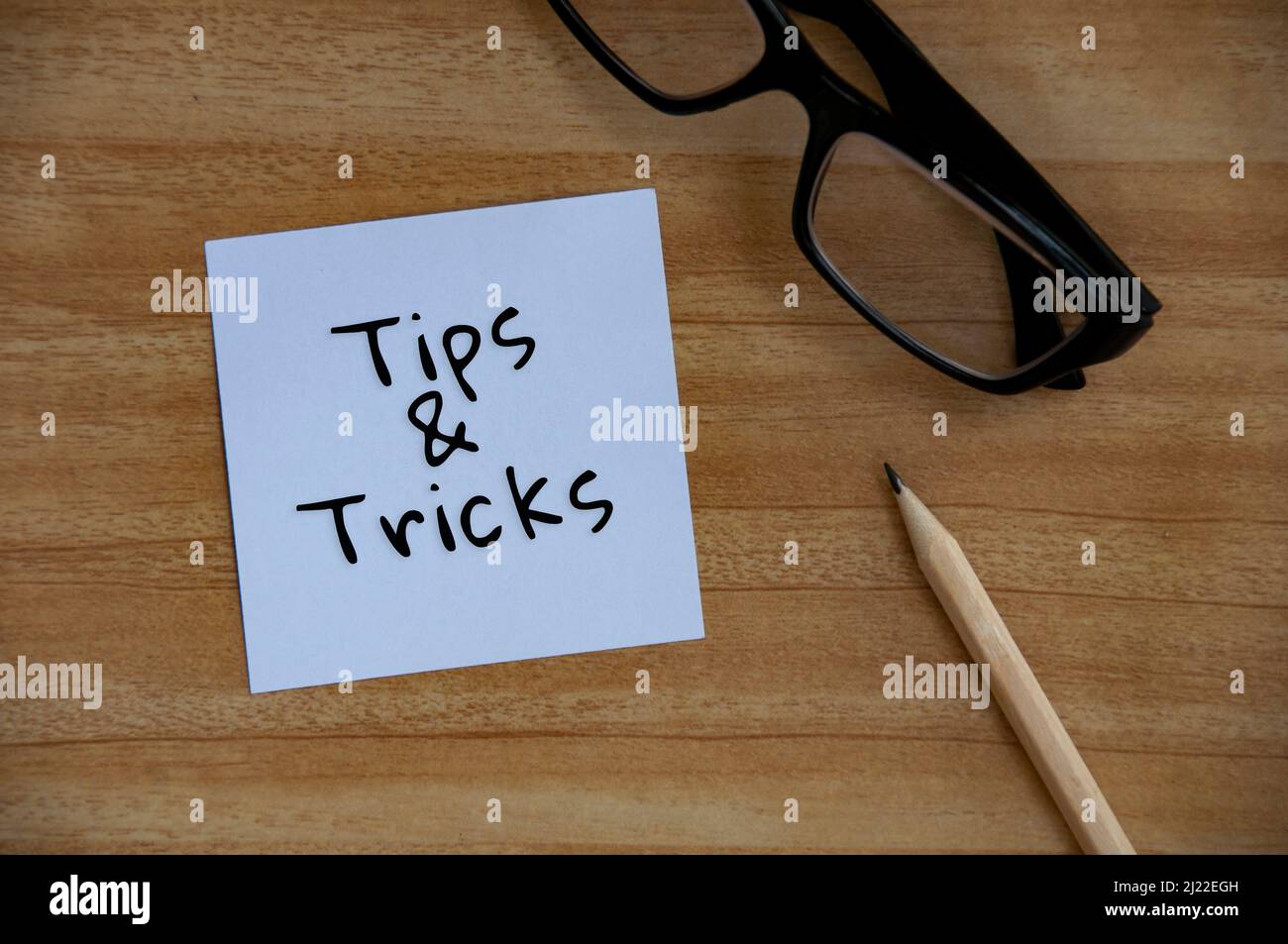 Tips and Tricks Text auf weißem Notizblock mit Brille und Bleistifthintergrund. Konzeptionell Stockfoto