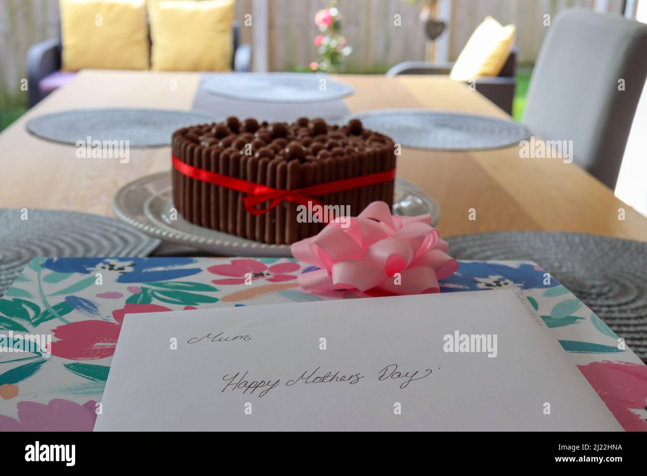Muttertagskarte, Geschenk und Kuchen auf einem Tisch Stockfoto