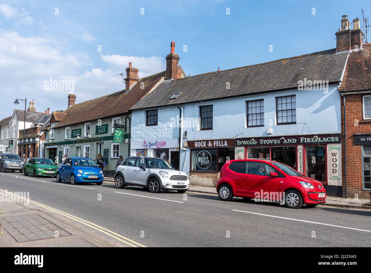 Blick auf die Straße entlang einer befahrenen Straße im Dorf Liphook, Hampshire, England, Großbritannien, mit roten, Weiße und blaue Autos Stockfoto