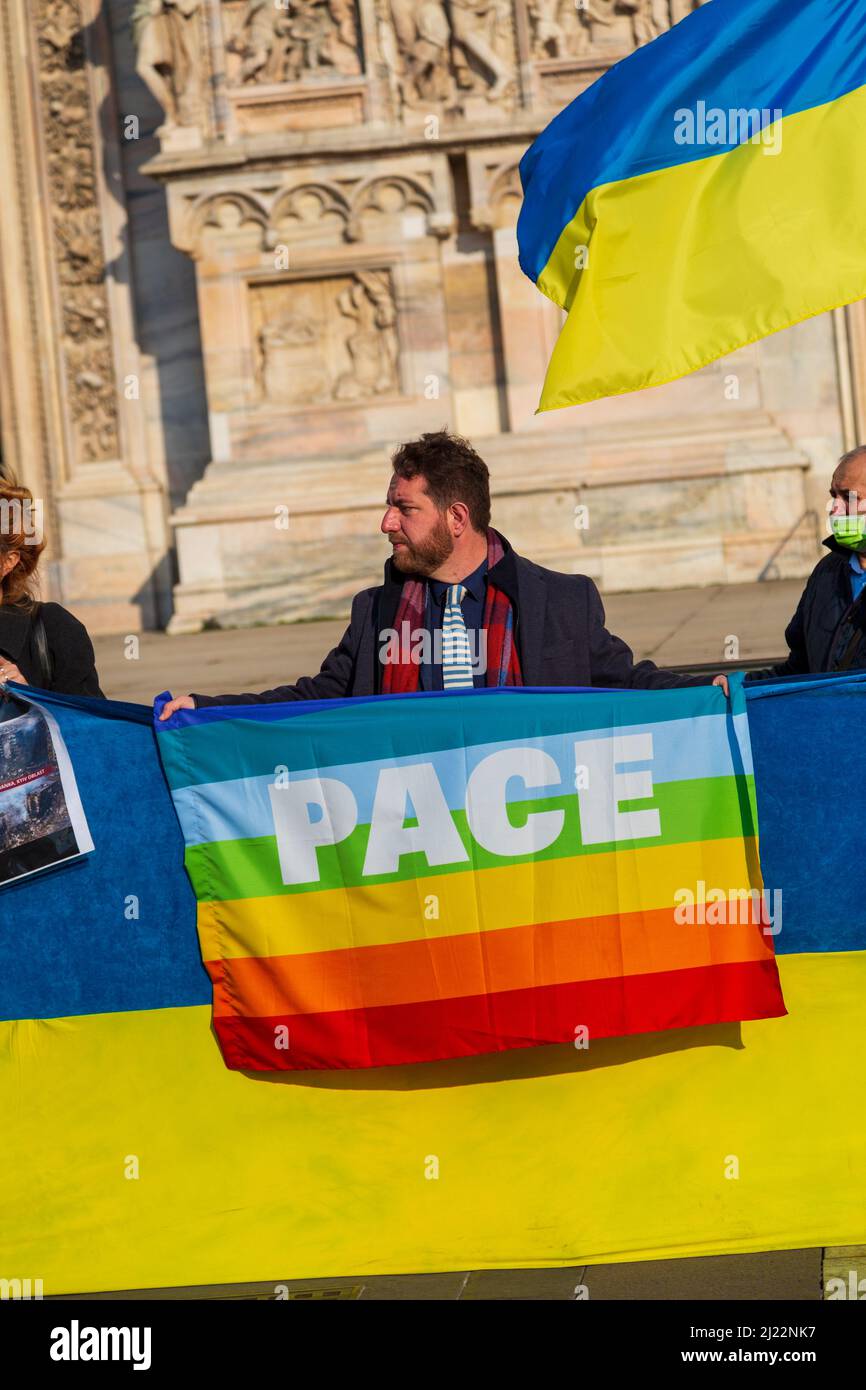 Ein Protest gegen den Ukraine-Krieg, ein Mann mit einer LGBT-Flagge mit dem Wort "Frieden" auf Italienisch in Mailand Stockfoto