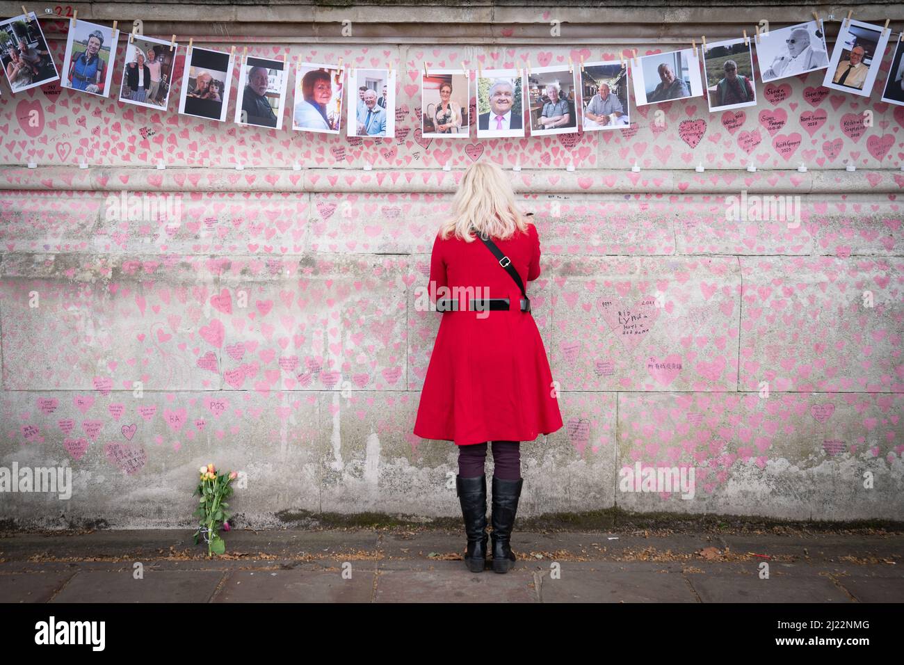 Ein Familienmitglied zahlt seinen Respekt für diejenigen, die Covid 19 ihr Leben verloren haben, während sie den einjährigen Jahrestag der National Covid Memorial Wall, London, begehen. Bilddatum: Dienstag, 29. März 2022. Stockfoto