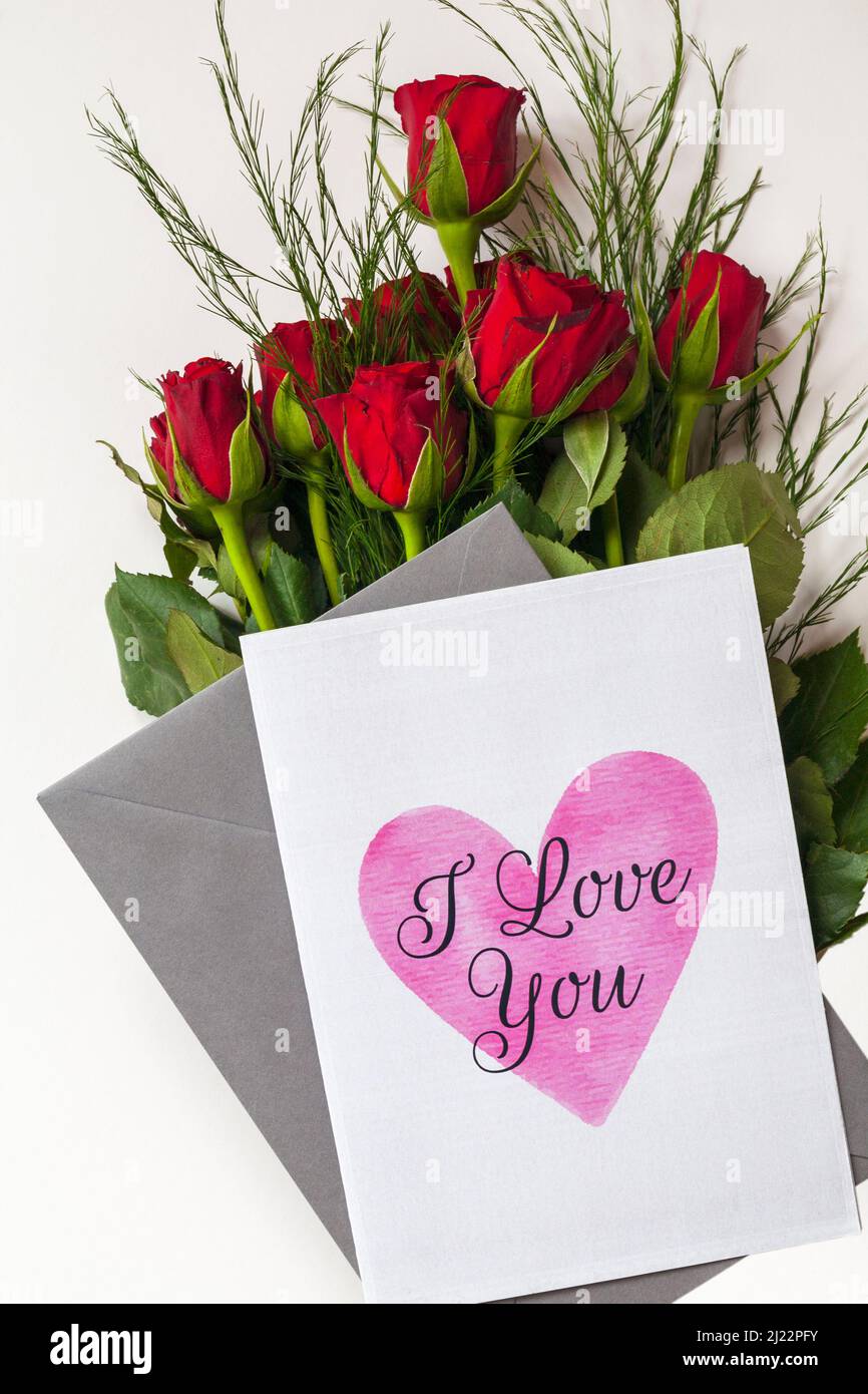 Ein Strauß roter Rosen mit „I Love You“ Valentinskarte für den Valentinstag auf weißem Hintergrund Stockfoto