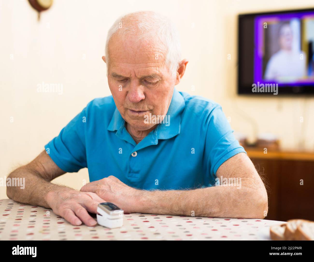 Besorgter älterer Mann, der sich zu Hause die Sauerstoffsättigung misst Stockfoto
