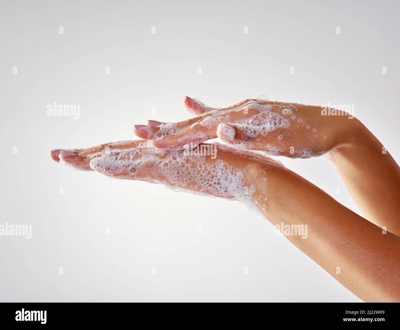 Eine gute Hygiene ist für die Gesundheit unerlässlich. Abgeschnittene Aufnahme von Händen, die mit Seife vor grauem Hintergrund gewaschen wurden. Stockfoto