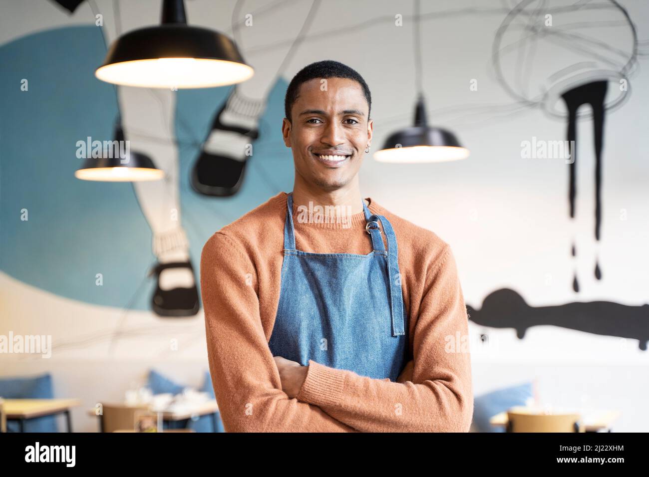 Lächelnder Besitzer oder Kellner in Arbeitsuniform stehen in moderner Cafeteria oder Restaurant Pub - Stellenangebot Konzept - Arbeiten in Catering Stockfoto