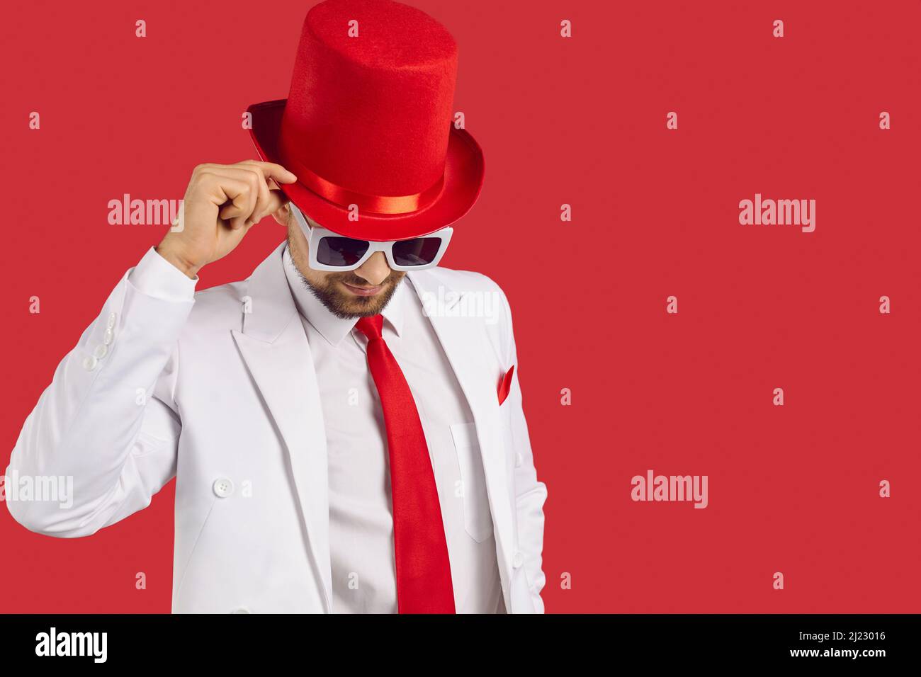 Porträt eines gutaussehenden Gentleman in weißem Anzug, rotem Zylinderhut und Brille auf dem Hintergrund des Kopierbereichs Stockfoto