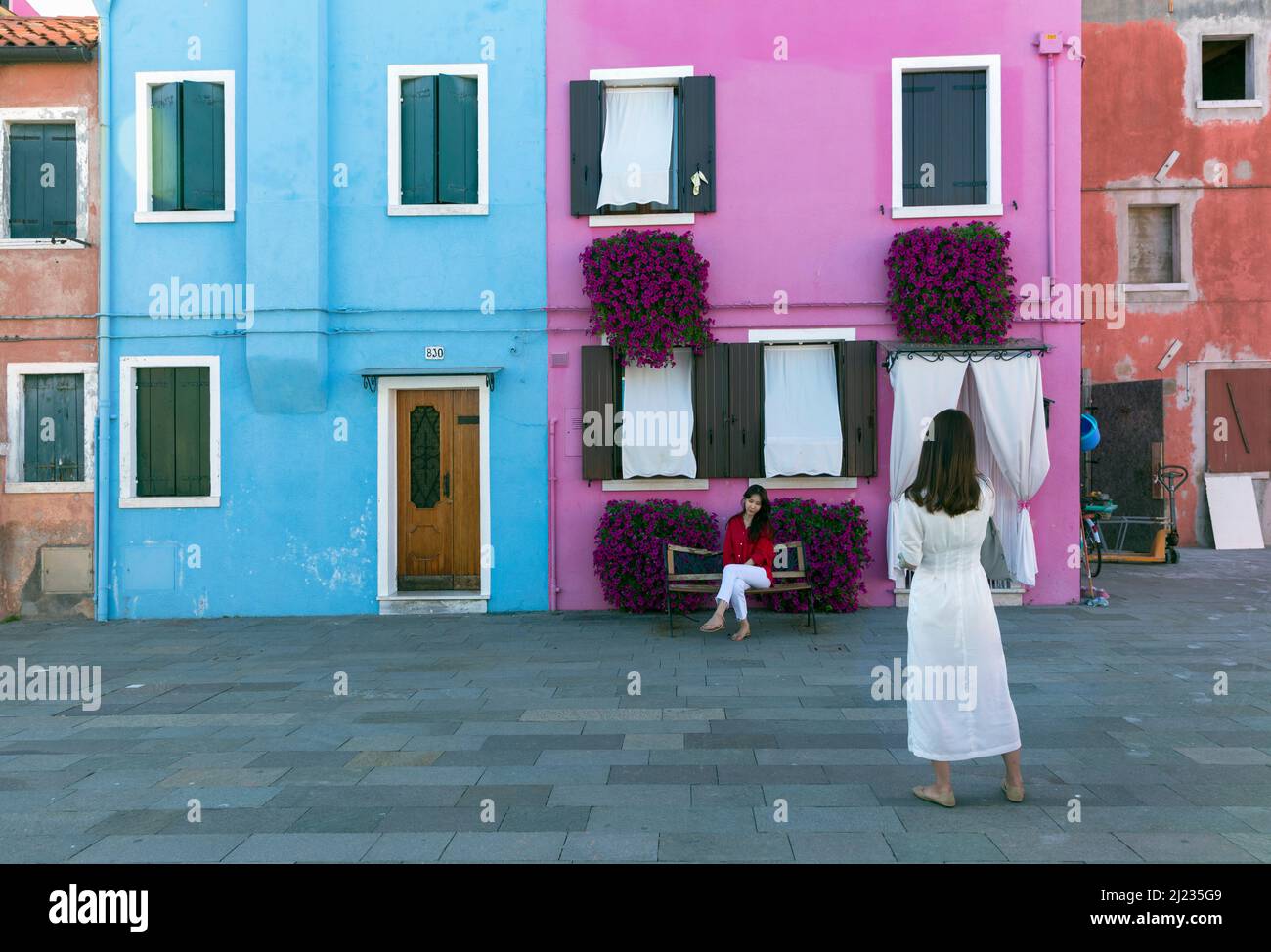 Italien, Venedig, farbenfrohe Häuser auf der venezianischen Insel Burano mit zwei posierten Frauen Stockfoto