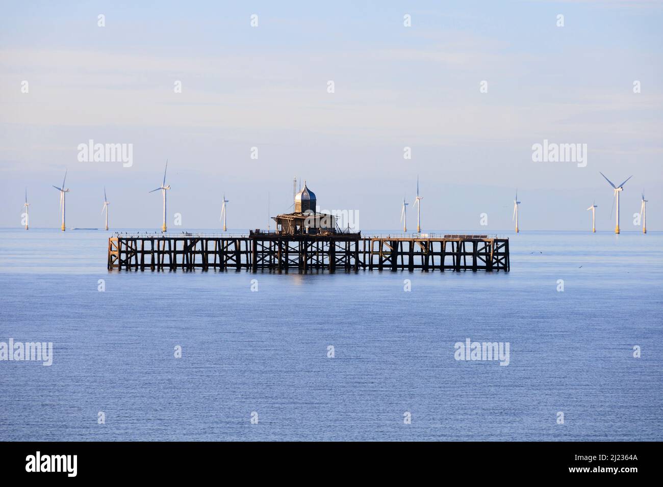 Vergängtes Ende des Piers mit den Offshore-Windparkturbinen von Kentish Flats. Herne Bay, Kent, England Stockfoto