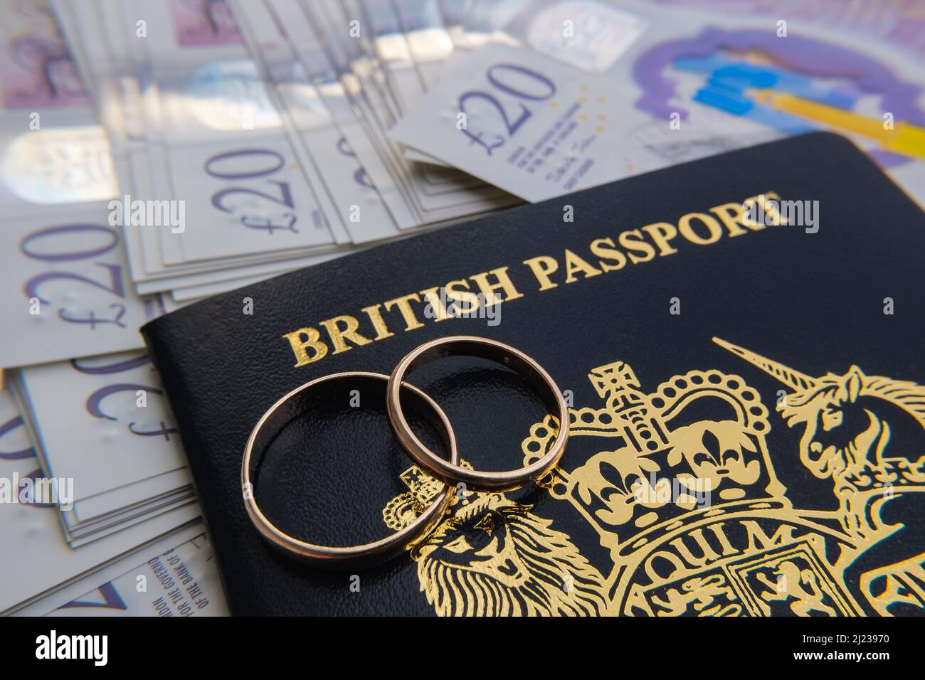 Goldene Ringe auf einem neuen dunkelblauen britischen Pass. Konzept für das britische Verlobungsvisum oder das Ehepartnervisum. Stafford, Großbritannien, 29. März 2022. Stockfoto
