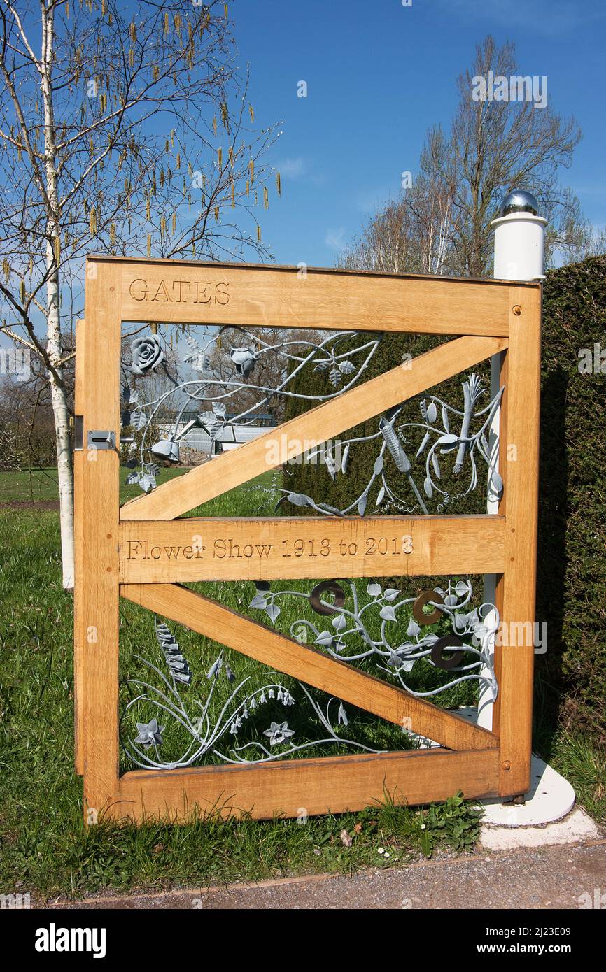 Holztor mit geflügeltem Blumenmuster aus Metall zum Gedenken an 100 Jahre Blumenschau 1918-2018 im RHS Wisley Garden, Surrey, England Stockfoto