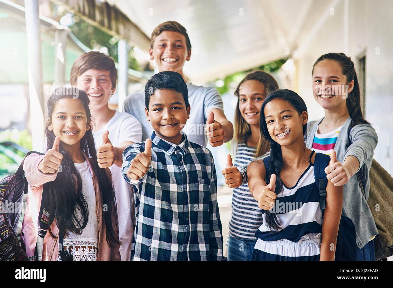 Unsere Schule ist sehr cool. Porträt einer Gruppe glücklicher Schüler mit Daumen nach oben außerhalb ihres Klassenzimmers. Stockfoto