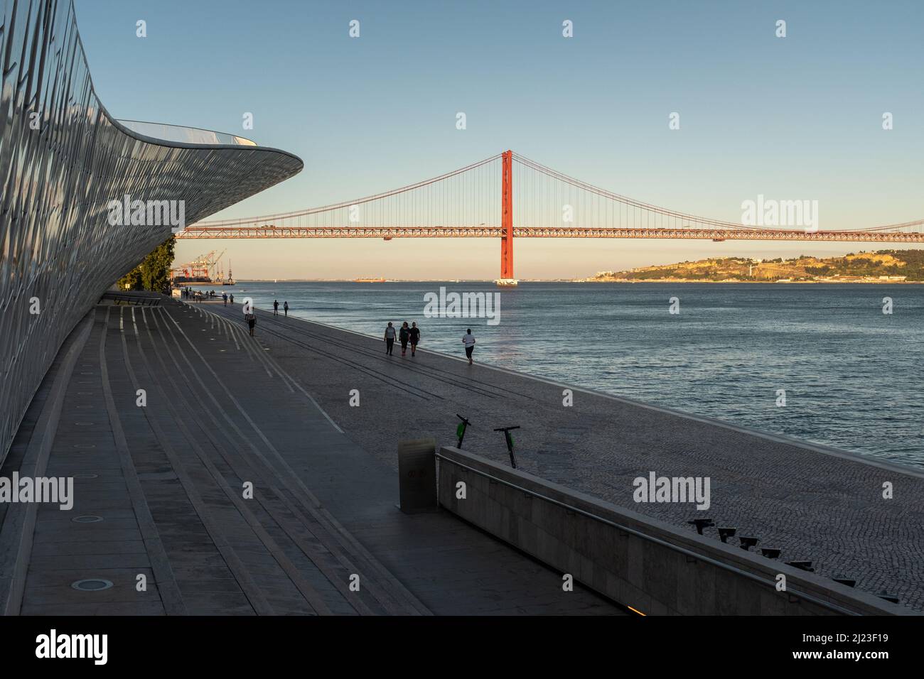 Lissabon, Portugal: Menschen spazieren im MAAT - Museum für Kunst, Architektur und Technologie. Der Tejo und die Brücke vom 25. April im Hintergrund. Stockfoto