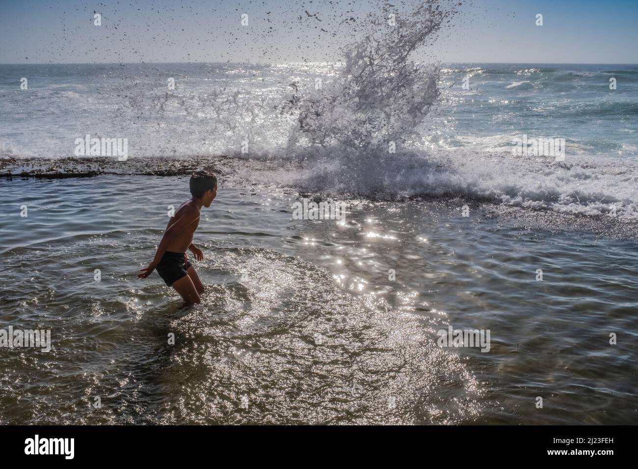 Das Kind genießt im Azenhas do Mar Colares Sintra große hohe Wellen, die plätschern Stockfoto