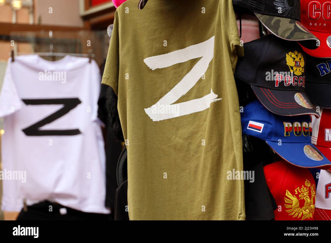 T-Shirts mit den Buchstaben Z und V, Baseballkappen mit Aufschrift Russland in einem Souvenirshop. Anzeichen einer russischen Militäroperation in der Ukraine Stockfoto