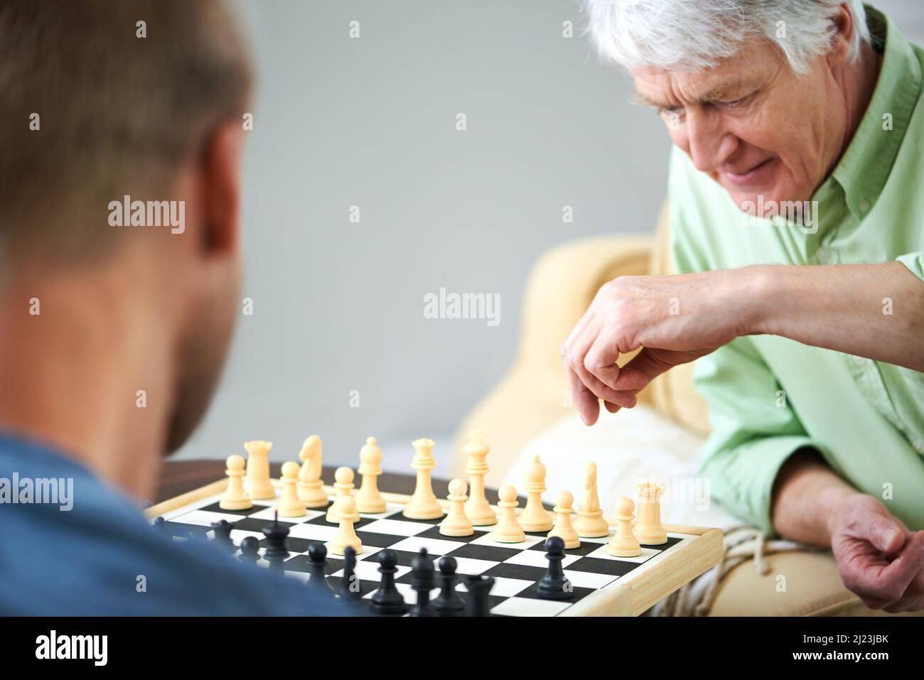 Lernen vom Meister des Schachs. Aufnahme eines Vaters und eines Sohnes, der zu Hause gemeinsam ein Schachspiel spielt. Stockfoto