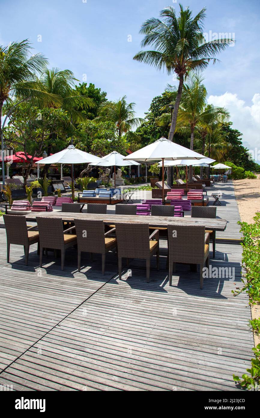 Sonnenliegen, Tische, Stühle am Strand im Griya Santrian Hotel in Sanur, Bali, Indonesien. Stockfoto