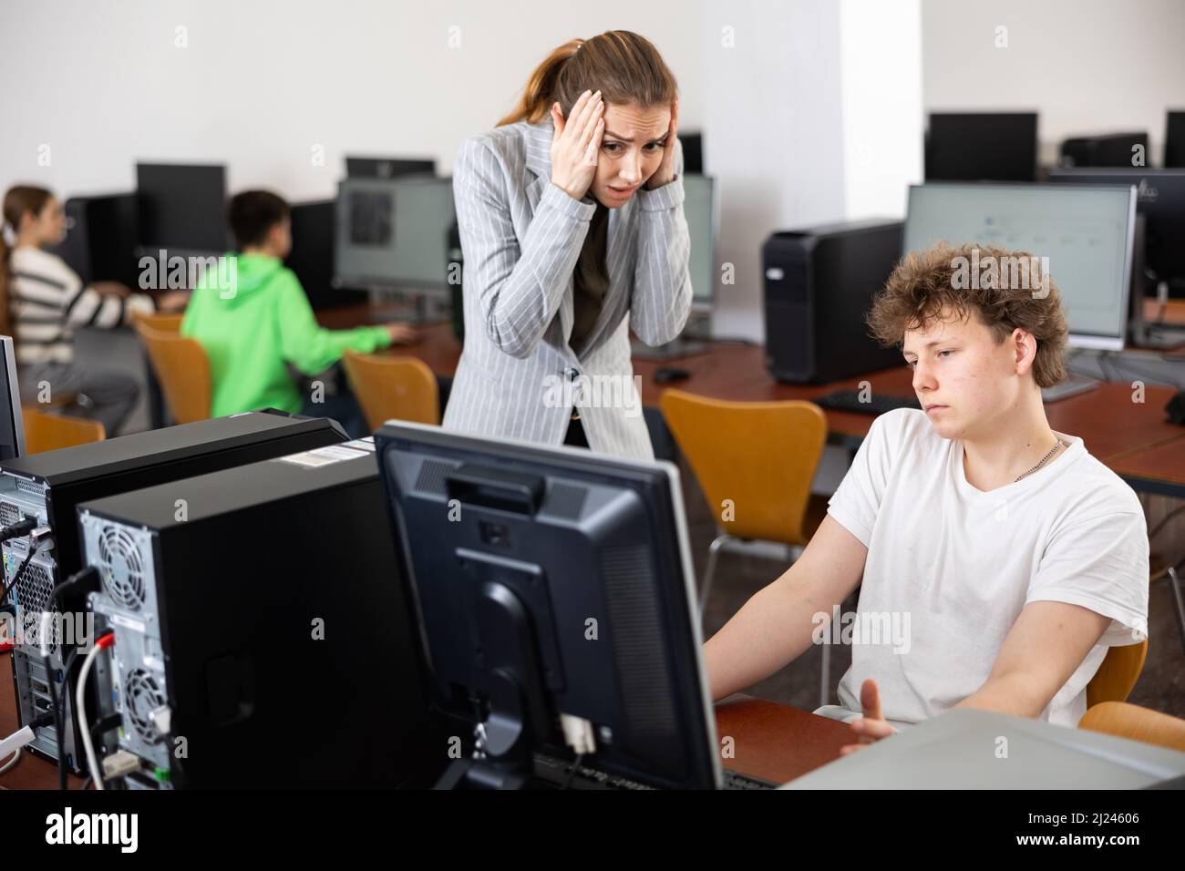 Lehrer erstaunt über Fehlverhalten des Teenagers während des Informatikunterrichts Stockfoto