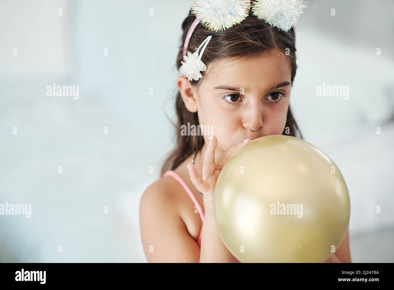 Ich möchte sehen, wie groß es wird. Aufnahme eines entzückenden kleinen Mädchens, das bei ihrer Geburtstagsfeier einen Ballon in die Luft sprengen würde. Stockfoto