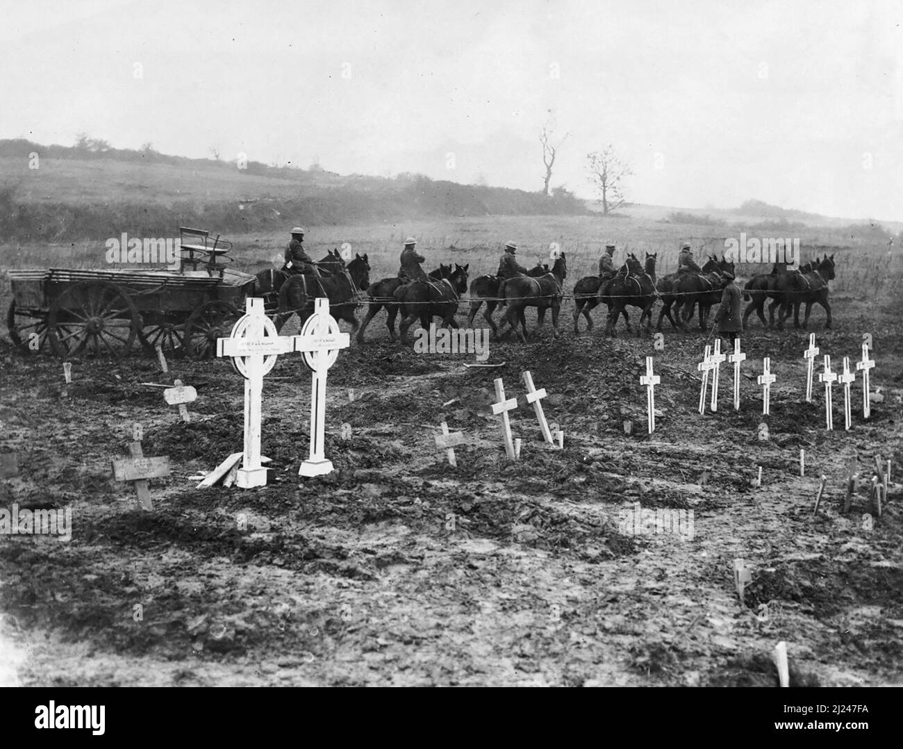 Ein zwölfköpfiges Team, wahrscheinlich des Armeedienstkorps, schleppt einen G.S.-Wagen (Generaldienst), über rauem, schlammigem Boden, in der Nähe von Bernafay Wood, September 1916. Im Vordergrund sind die hölzernen Grabmarkierungen eines temporären Friedhofs zu sehen. Stockfoto
