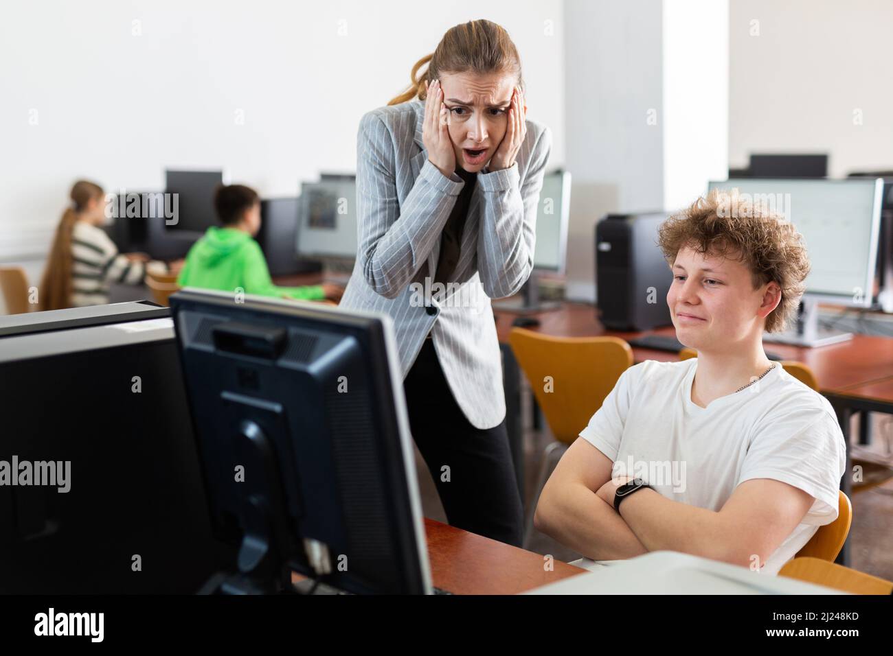 Lehrer erstaunt über Fehlverhalten des Teenagers während des Informatikunterrichts Stockfoto