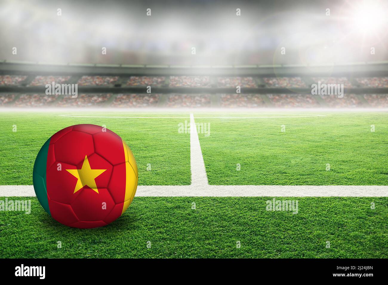 Fußball im hell erleuchteten Stadion mit der Flagge Kameruns. Konzentrieren Sie sich auf den Vordergrund und den Fußball mit geringer Schärfentiefe im Hintergrund Stockfoto