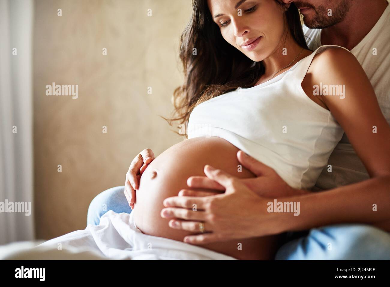 Bindung mit dem Baby. Aufnahme eines Mannes und einer Schwangeren, die in einem Schlafzimmer sitzen. Stockfoto
