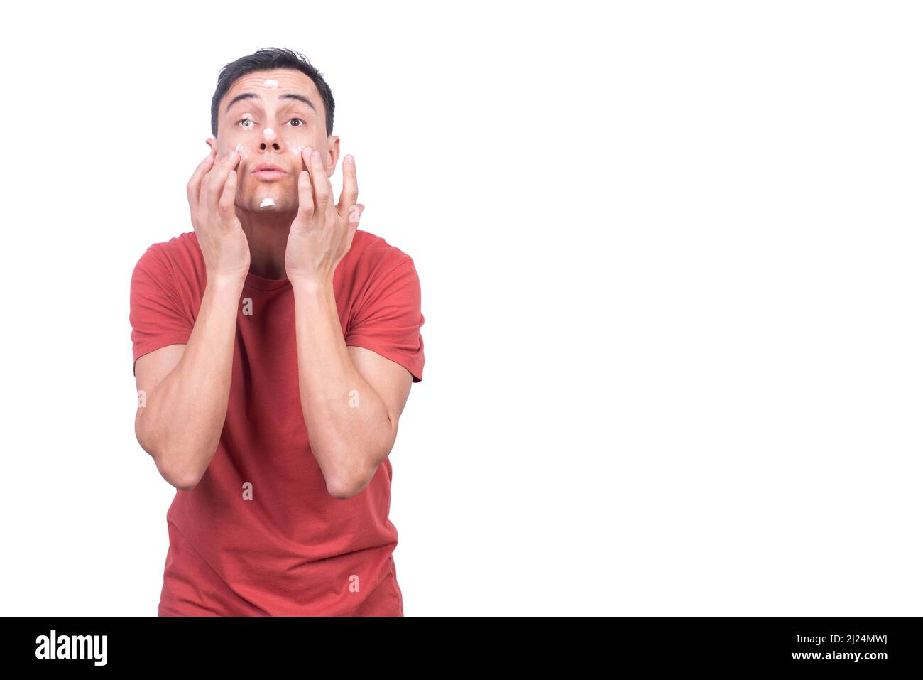 Mann, der feuchtigkeitsspendende Gesichtscreme auf weissem Hintergrund anwendet Stockfoto