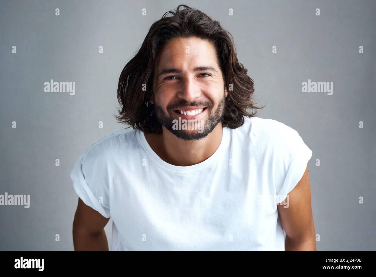 Das Lächeln, das tausend Herzen schmolz. Studioaufnahme eines hübschen jungen Mannes, der vor einem grauen Hintergrund posiert. Stockfoto
