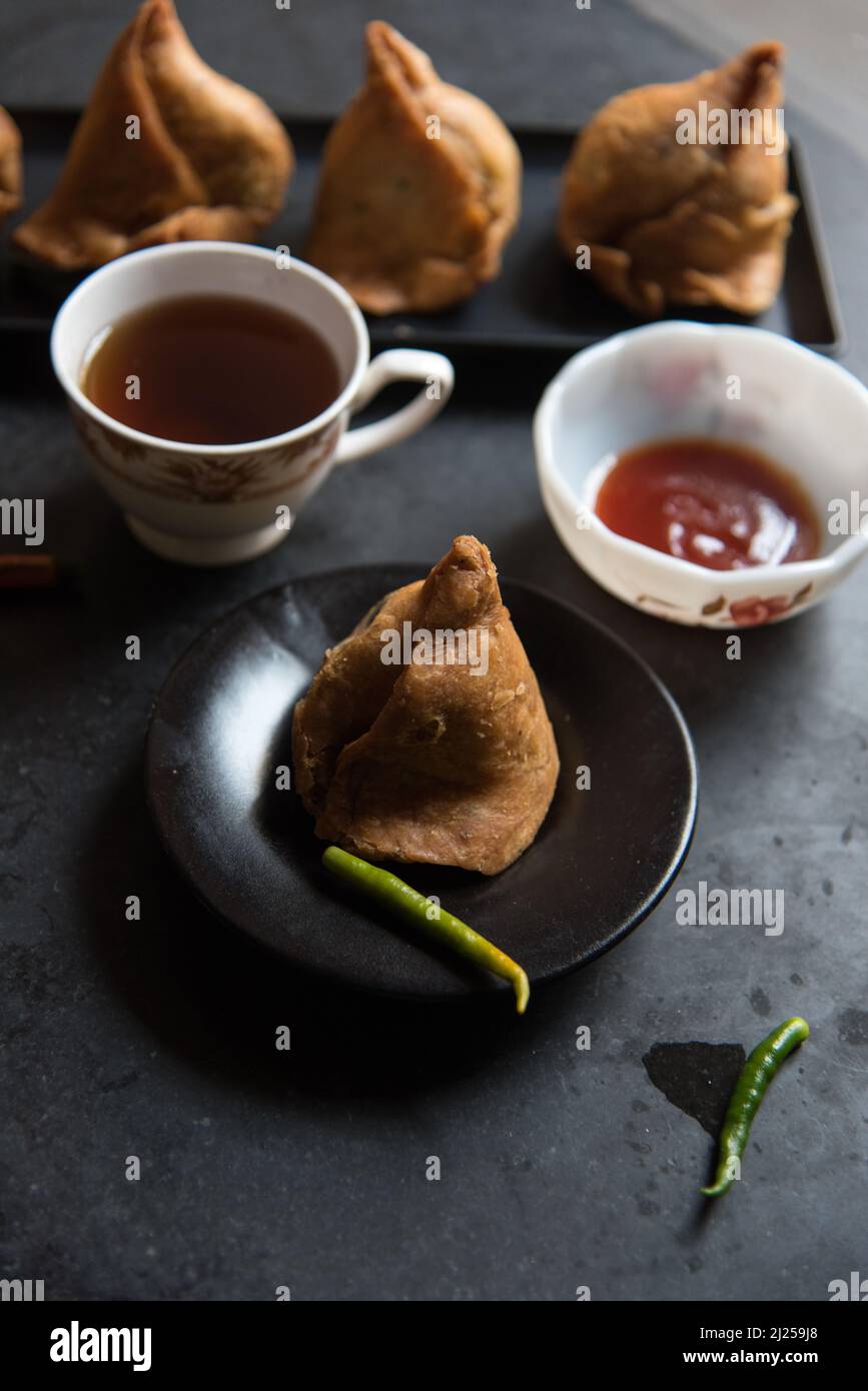 Indische Snacks Samosa oder dreieckige frittierte Speisen auf dunklem Hintergrund Stockfoto