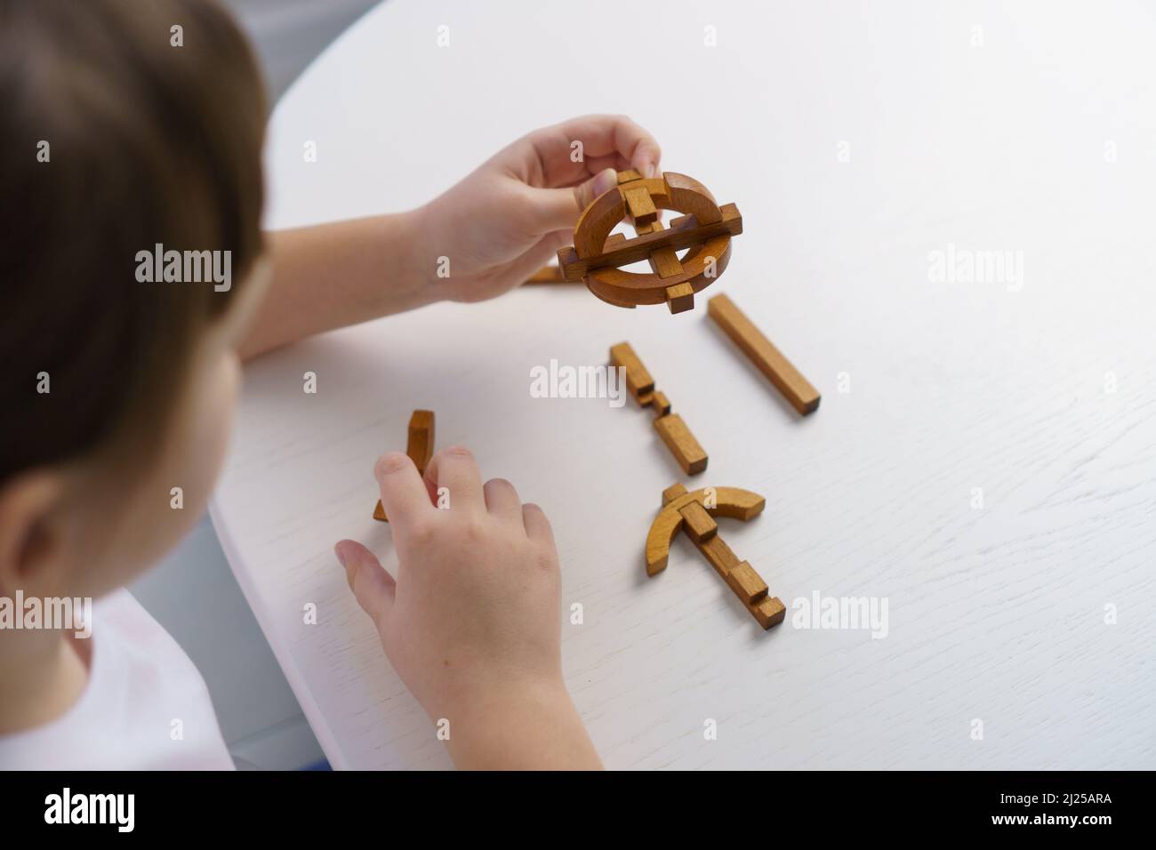 Kleines Mädchen spielt zu Hause mit hölzernen Puzzle-Blöcken. Konzept für die Entwicklung und Bildung von Kindern Stockfoto