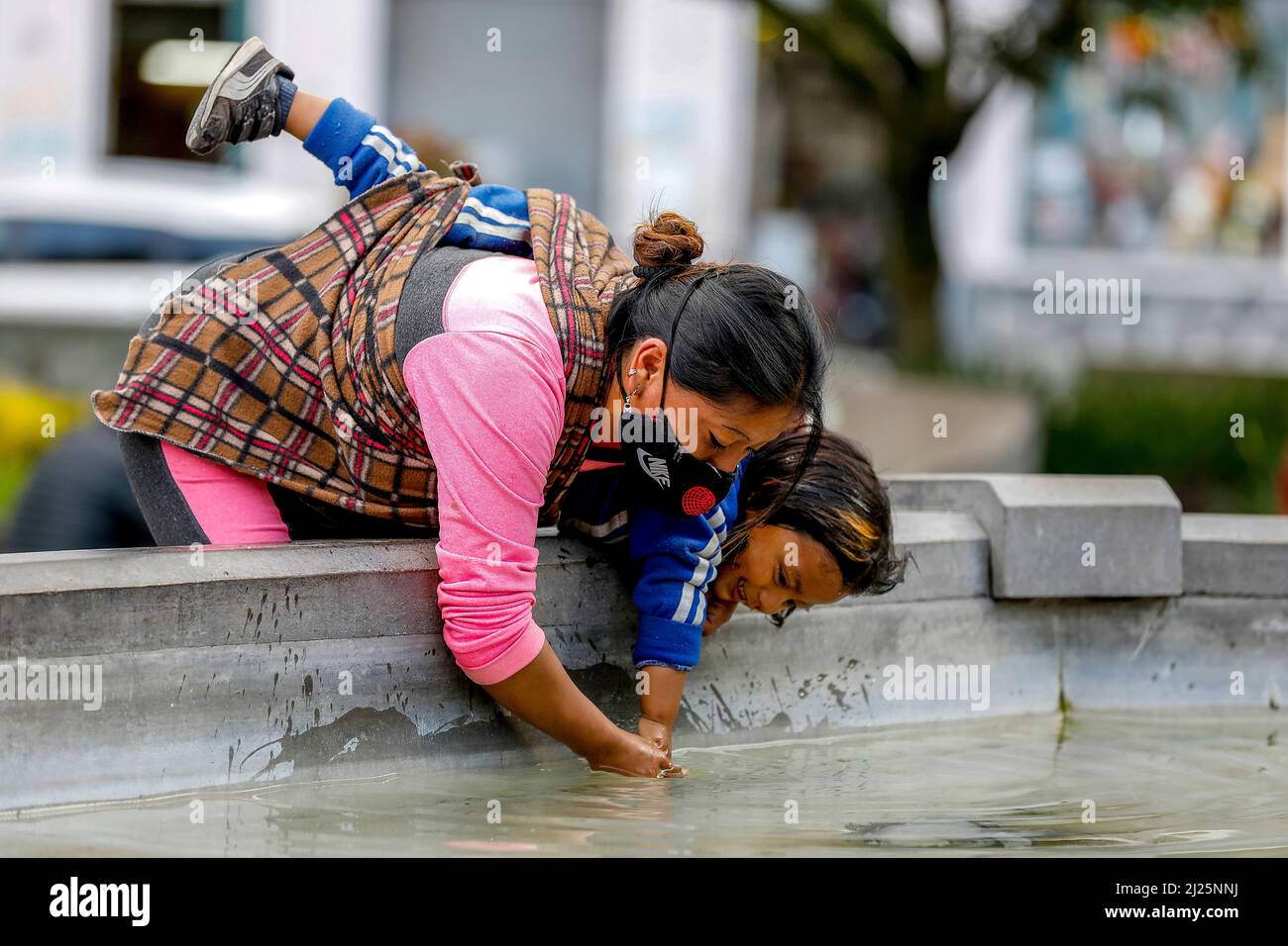 Frau, die ihre Tochter in einem öffentlichen Park in Riobamba, Ecuador, wäscht Stockfoto