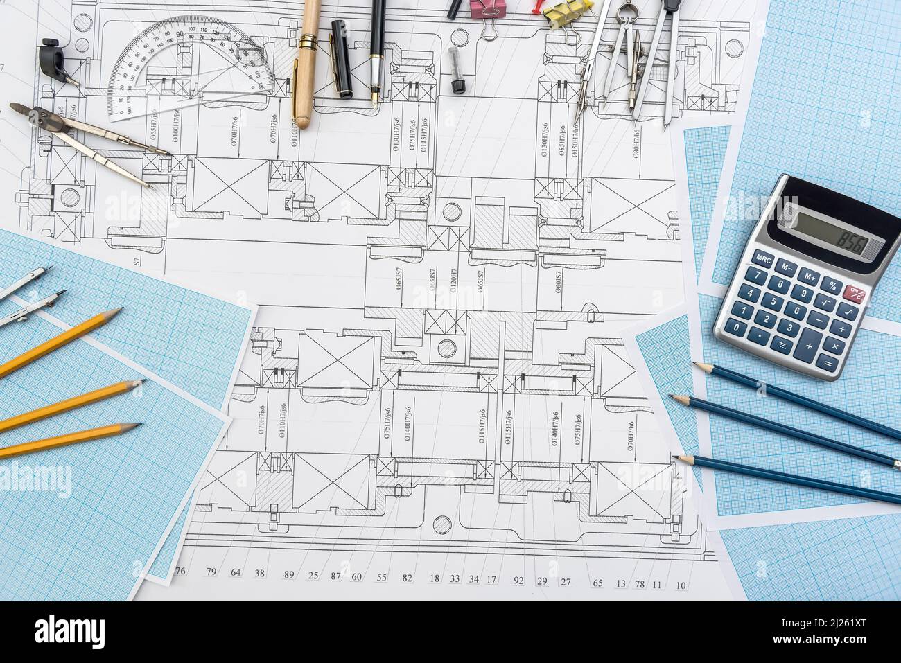 Papier mit technischen Zeichnungen und Arbeitswerkzeug auf Tisch. Ort der Arbeit Stockfoto