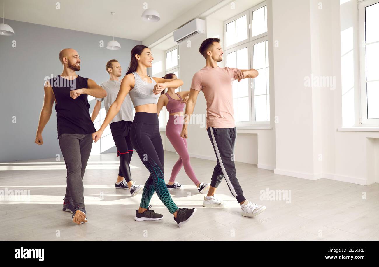 Eine Gruppe glücklicher sportlicher Menschen, die einen Tanz- oder Fitnesskurs mit einem Trainer absolvieren Stockfoto