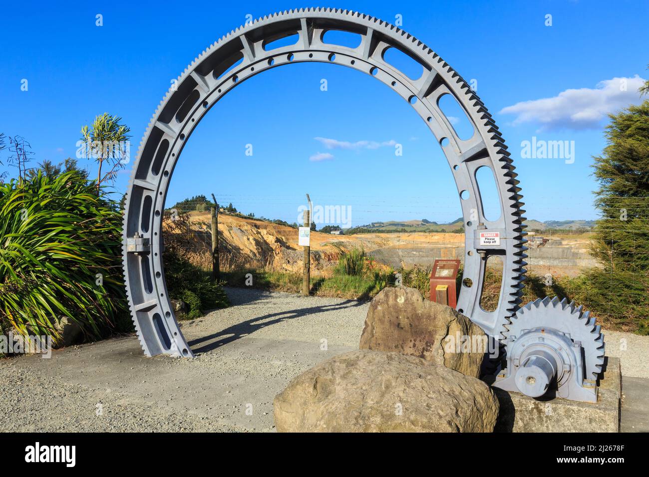 Ein riesiges Zahnrad, das einst zum Zerkleinern von Erz verwendet wurde, diente als Torbogen bei der Goldmine Martha in Waihi, Neuseeland Stockfoto